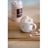 kopp med teksten det beste er å dele på bord med kakao og marshmallows