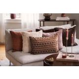 Sofa fylt med puter i beige, brun, rosa og rustbrune farger