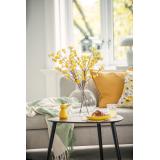 Påskegul kai fugl på bord med glassvase og gule blomster og gult påskeservice