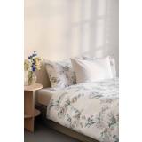 Satengsett med blomster motiv og i hvitt i seng