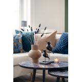 Sofabord pyntet med beige vase med strå i ved siden av fuglefigurer på pinne 