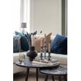 Pyntet sofabord med sort vase og grå kronelysestaker i glass med sofa i bakgrunnen