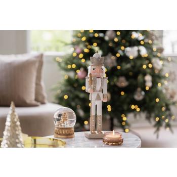 Nøtteknekker på sofabord med snøkule og duftlys ved siden av lysfat