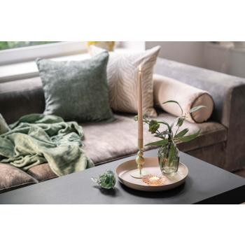 Sofakrok med puter og pledd og et lysfat med vase og lysestake på bordet