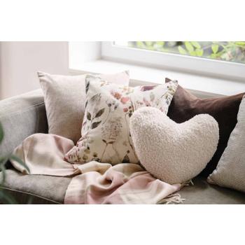 Sofakrok med puter og et pledd i rosa toner