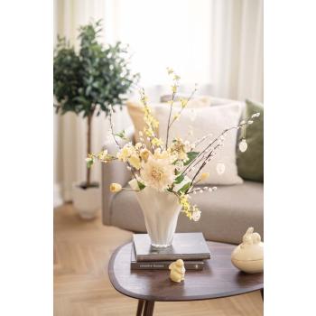 Vase med en bukett av gule blomster og glassegg