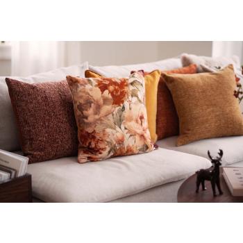 Sofa fylt med puter i oransje, gule og brune toner