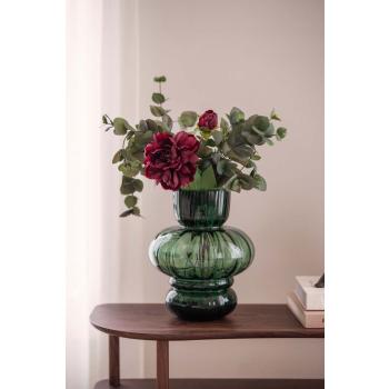 Stilkblomst Peon og gren eucalyptus i grønn vase