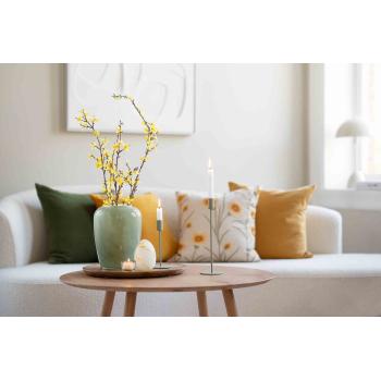 Puter i sofa i gul og grønntoner ved sofabord med vase og lysestaker