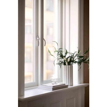 Vase, stilkblomst, bøker og telysholder i vinduskarm